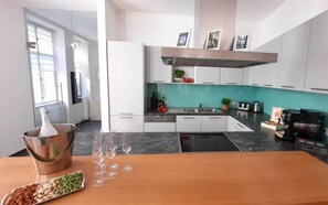 Une cuisine moderne avec des armoires blanches, un pare-feu turquoise et une hotte de cuisinière en acier inoxydable.