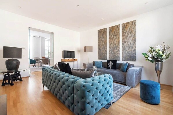 A modern living room with a blue sofa, grey sofa, and a coffee table.