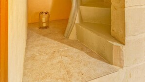 A stone-walled bathroom with a bathtub, a small window, and a tiled floor. - Cosy Maltese Townhouse, Roof Terrace and Views (Senglea)