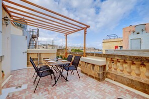 A rooftop terrace with a pergola, dining table, chairs, and a view of the cityscape. - Cosy Maltese Townhouse, Roof Terrace and Views (Senglea)