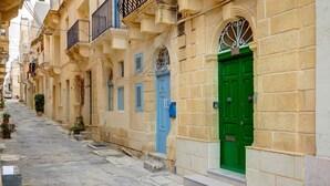 A narrow street lined with traditional buildings featuring stone facades and colorful doors. - Cosy Maltese Townhouse, Roof Terrace and Views (Senglea)