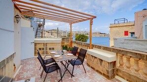 A terrace with a table set for two, overlooking a body of water and a cityscape. - Cosy Maltese Townhouse, Roof Terrace and Views (Senglea)