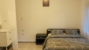 Een slaapkamer met een bed, nachtkastje en een wandlamp.