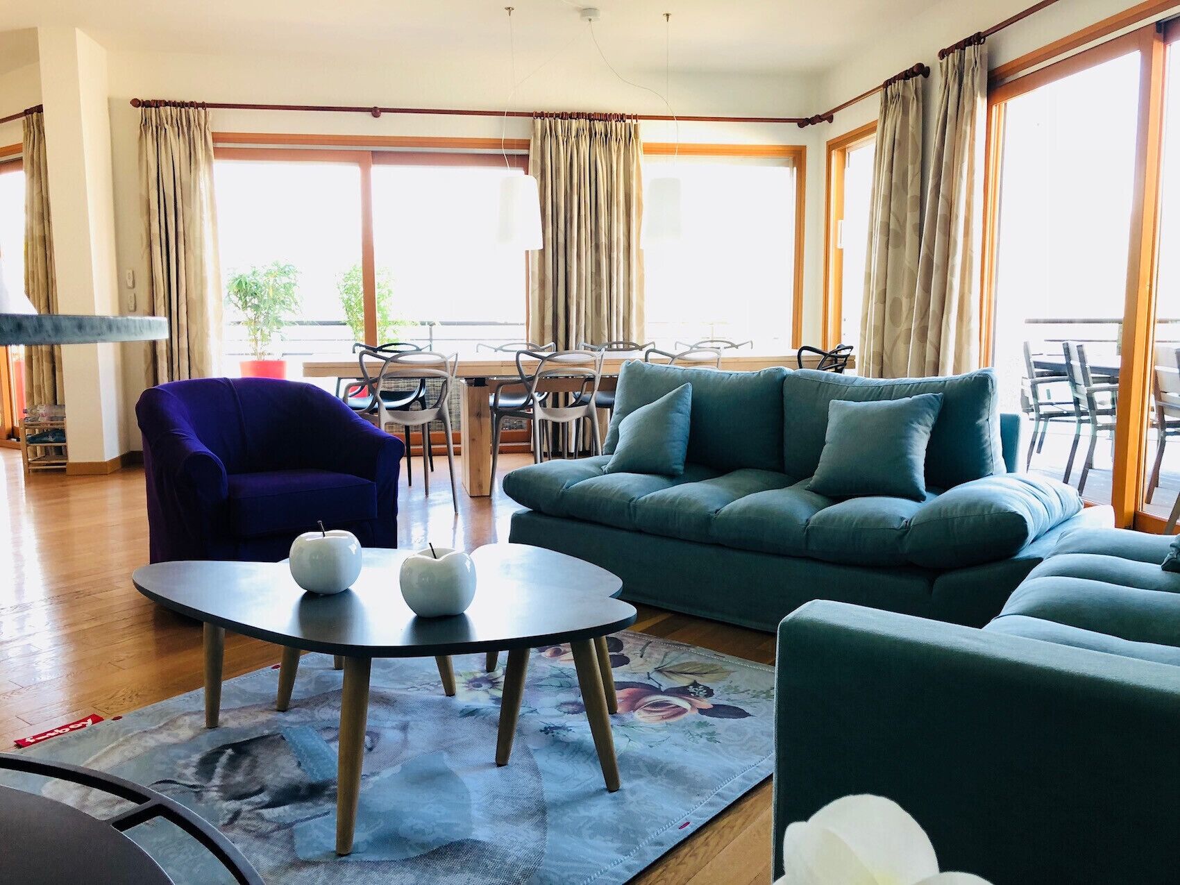 Un salon comprenant un canapé, un fauteuil, une table basse ronde et un coin repas avec des chaises et une table.