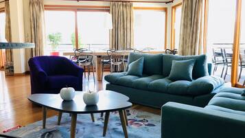 Un salon comprenant un canapé, un fauteuil, une table basse ronde et un coin repas avec des chaises et une table.