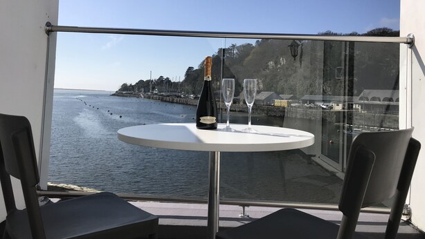 A balcony with a table, two chairs, a bottle of champagne, and two glasses. - Sea View Holiday Cottage Porthmadog (Porthmadog)