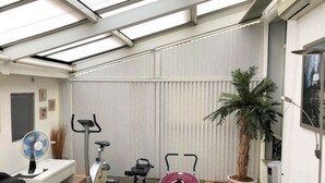 Uma academia compacta para casa com equipamentos de ginástica, um ventilador e um vaso de planta.