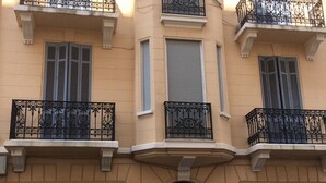Um edifício de vários andares com varandas, uma porta de garagem e uma placa com o número 24.