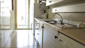 Een keuken met witte kastjes, een roestvrijstalen spoelbak en een ingebouwde wasmachine.