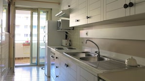 Een moderne keuken met witte kasten, een roestvrijstalen spoelbak en een magnetron.
