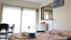 Een hotelkamer met een bed, een stoel, een tafel, een spiegel en een raam met gordijnen.