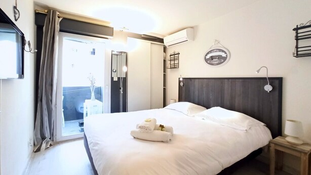 Una habitación de hotel con cama, mesita de noche, cortinas y aire acondicionado.