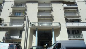 Un edificio de varios pisos con balcones, una entrada central y un cartel que dice "LE PALAZZOIO".