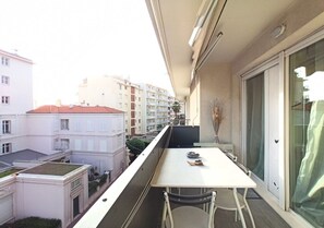 A balcony with a table and chairs, overlooking a residential area with buildings. - Viva Riviera Residence Palazzio 1 Bedroom  Bellevue (Cannes)