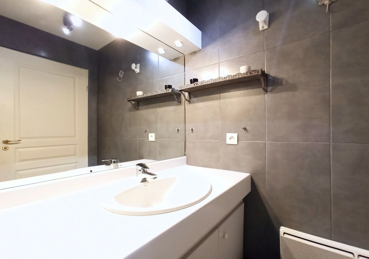 A modern bathroom with a large sink, a mirror, and two shelves above the sink.