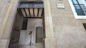 Entrada de un edificio con fachada de piedra, un escudo sobre la puerta y un letrero que dice "Casa Font".