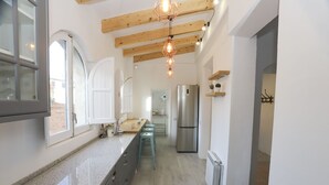 Una cocina moderna con una isla grande, electrodomésticos de acero inoxidable y techo de madera.