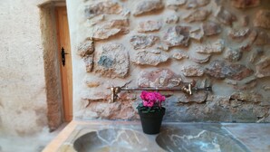 Un baño con un lavamanos de piedra, una planta en maceta y una pared de piedra.