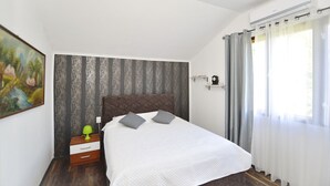 A bedroom with a bed, a nightstand, a wall-mounted shelf, and a window with curtains. - Luxury house with private pool, sauna, hot tub and river on the property (Danilovgrad)