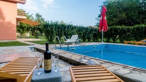 A swimming pool with lounge chairs and a bottle of wine on the deck. - Luxury house with private pool, sauna, hot tub and river on the property (Danilovgrad)
