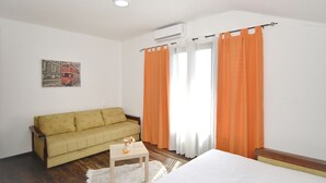 A room with a bed, a sofa, a small table, and a wall-mounted clock. - Luxury house with private pool, sauna, hot tub and river on the property (Danilovgrad)