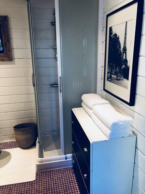 Bathroom features a glass shower door, a towel on a cabinet, and a framed photograph on the wall.