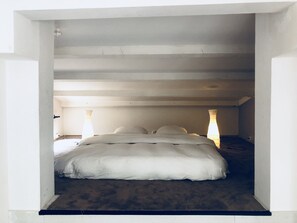Cozy retreat with a single bed, bedside lamps, and sloped ceiling.