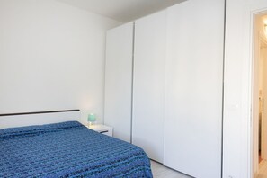 Ett sovrum med en säng, ett nattduksbord, en lampa och en garderob.