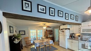 A kitchen with white cabinets, a dining area with a table and chairs, and a ceiling fan.