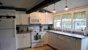 A kitchen with white cabinets, a microwave, a stove, and a sink.