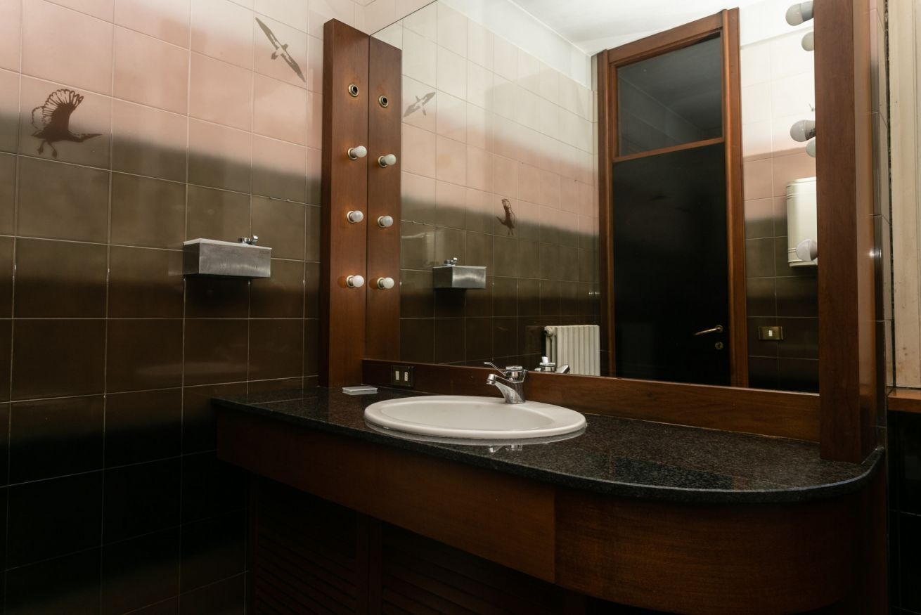 A bathroom with a sink, mirror, and towel rack.