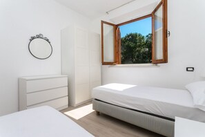 A bedroom with a bed, a dresser, a mirror, and a window with a view of trees. - N039 - Numana, villa with garden a stone's throw from the sea (Numana)