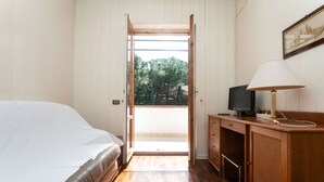 A bedroom with a bed, a desk with a lamp, and a TV.