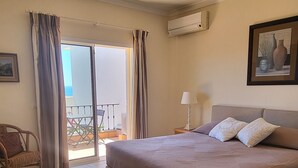 Une chambre d’hôtel avec un lit, une table de chevet, une lampe, une chaise, une fenêtre avec des rideaux et une vue sur l’extérieur.