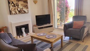 Un salon avec un canapé, une table basse, un téléviseur et une cheminée.
