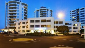 A hotel with multiple floors, a central entrance, and a parking area. - Spacious Large Modern Apartment in Fantastic Location (Tauranga)