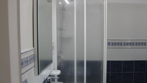 Une salle de bain avec un lavabo blanc, un miroir, des toilettes et un espace douche.
