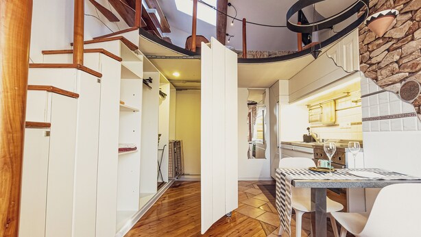 A modern interior with a wooden floor, white walls, and a kitchen area with a dining table and chairs. - Duplex Studio Apartment with Parking and Bike Storage in Chiavari (Chiavari)