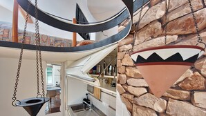 A kitchen with a stone wall backsplash, a hanging pot rack, and a built-in oven. - Duplex Studio Apartment with Parking and Bike Storage in Chiavari (Chiavari)