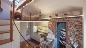 A compact kitchen with a stone wall, a dining area with a table and chairs, and a view of boats through a glass door. - Duplex Studio Apartment with Parking and Bike Storage in Chiavari (Chiavari)
