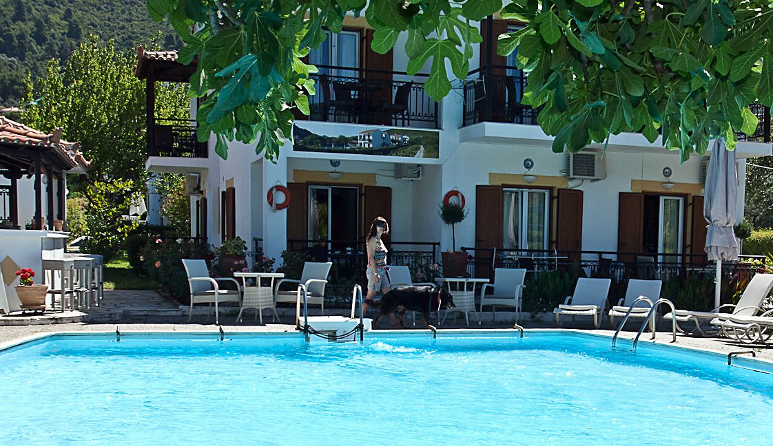 A swimming pool with lounge chairs and a building with balconies in the background.