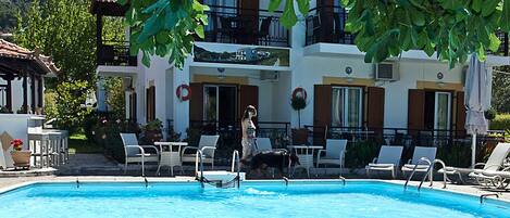 A swimming pool with lounge chairs and a building with balconies in the background.