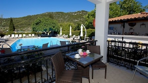 A balcony with wicker furniture, a pool, and a bar area with bottles.