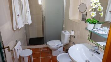 A bathroom with a toilet, bidet, sink, and shower.
