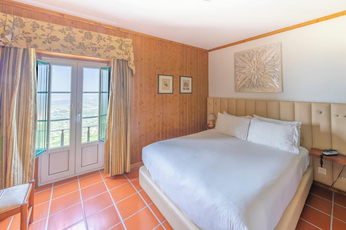 Ein Schlafzimmer mit einem großen Bett, Holzwandverkleidung, Blick durch eine Tür und einem an der Wand hängenden Kunstwerk.