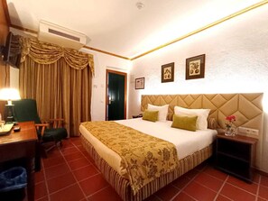 A hotel room with a bed, a desk, a chair, an air conditioning unit, and a door. - Hotel Dom Manuel (Marvao)