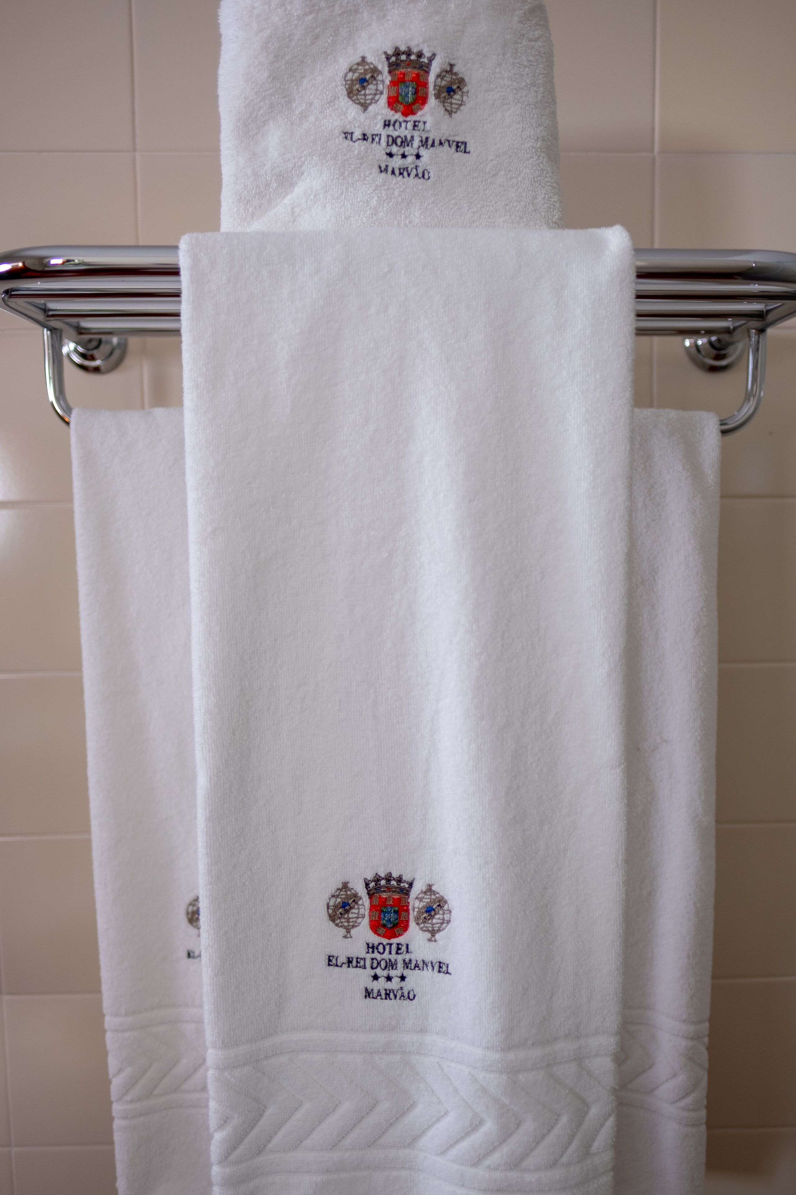 Two white towels hanging on a metal towel rack in a bathroom.