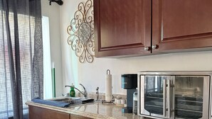 A kitchen with wooden cabinets, a stainless steel refrigerator, and a coffee maker.