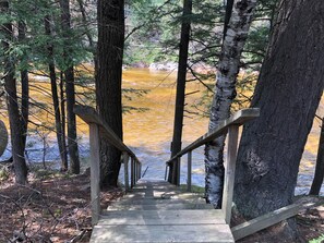 A wooden staircase leading down to a river surrounded by trees.