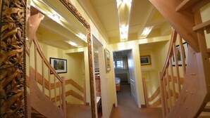 Un couloir avec des escaliers en bois, un miroir et des tableaux encadrés accrochés aux murs.